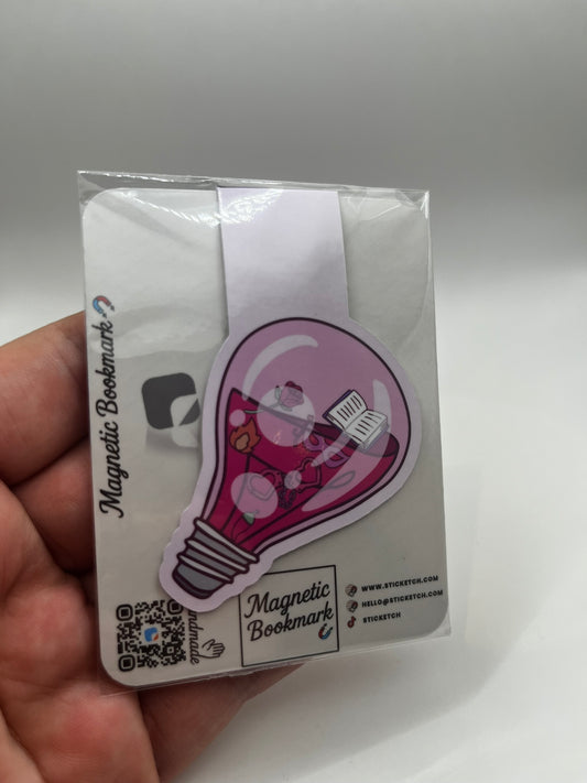 Magnetic bookmark with a light bulb design held in hand against a white background